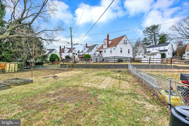 view of yard featuring a vegetable garden, fence, and a residential view