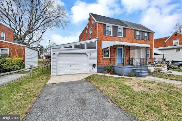 view of front facade with a front yard, fence, driveway, an attached garage, and brick siding