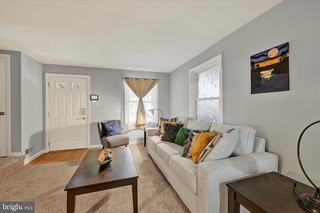 living area with baseboards, visible vents, and light carpet