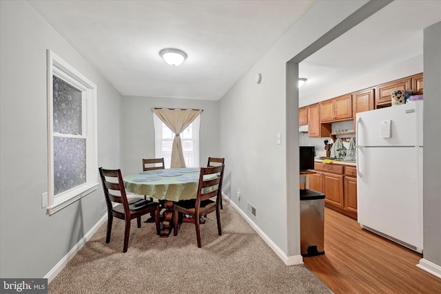 dining room featuring light wood finished floors, visible vents, and baseboards