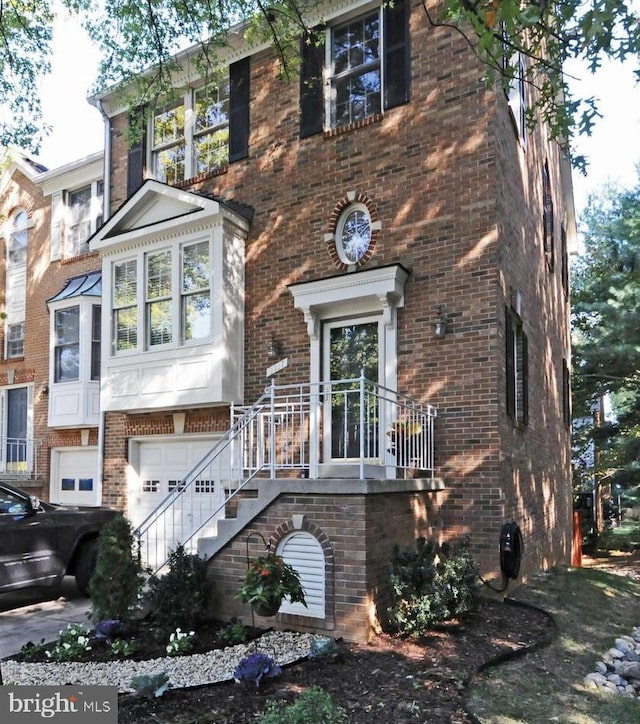 view of front of home featuring brick siding, an attached garage, and stairs