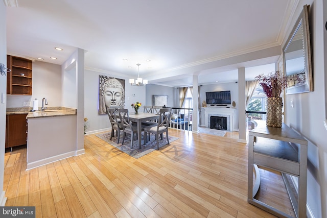 dining space with light wood-style flooring, a fireplace, baseboards, and ornamental molding