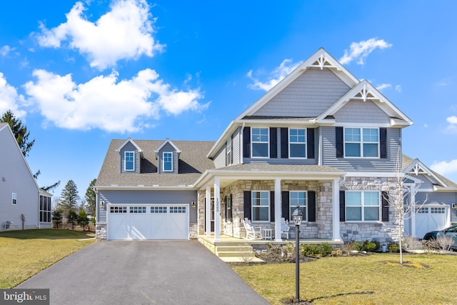 craftsman house featuring driveway, a front lawn, stone siding, covered porch, and a garage