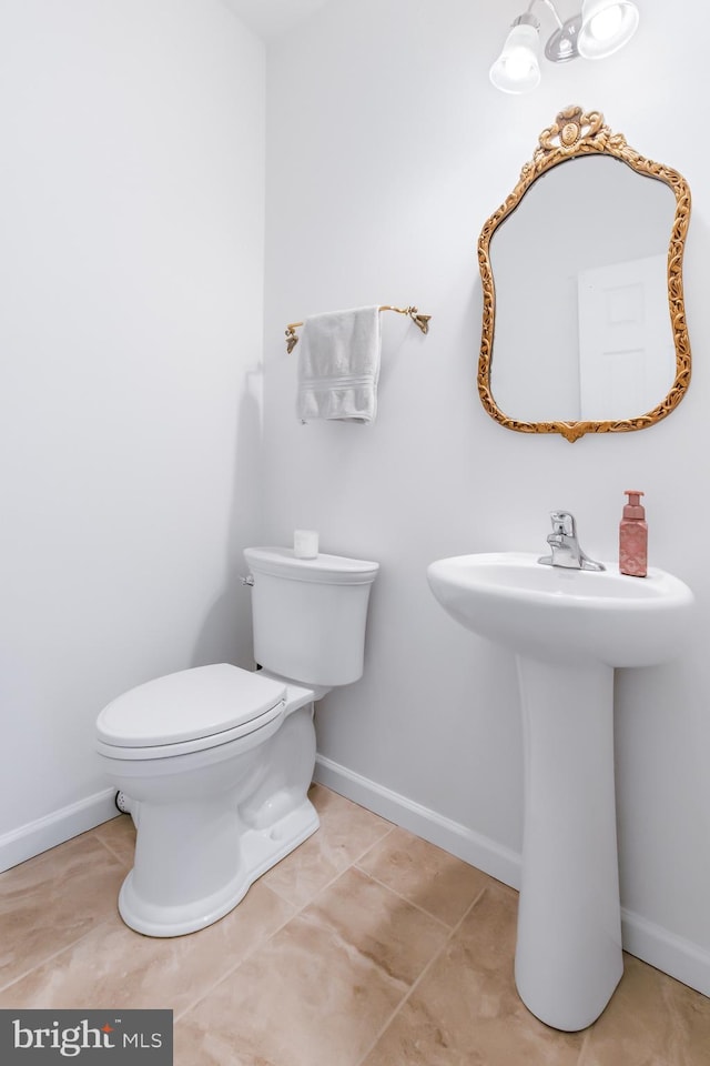 half bathroom with tile patterned floors, toilet, and baseboards