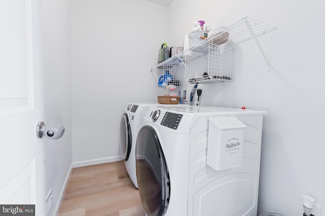 washroom with laundry area, independent washer and dryer, baseboards, and light wood-style floors