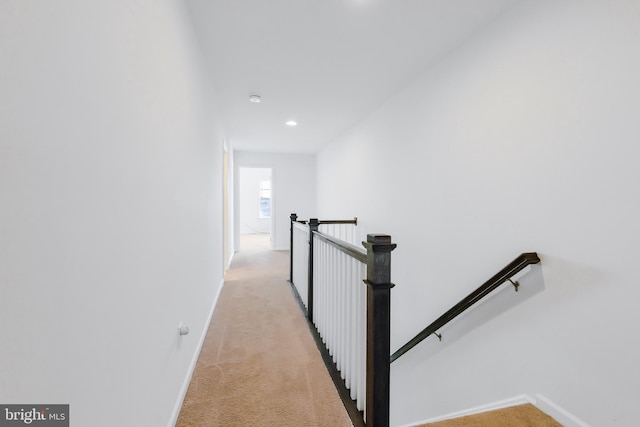 hall with recessed lighting, baseboards, light carpet, and an upstairs landing