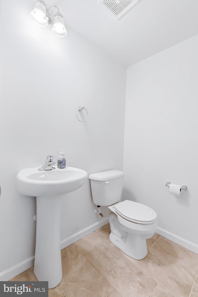 half bath with tile patterned flooring, visible vents, toilet, and baseboards