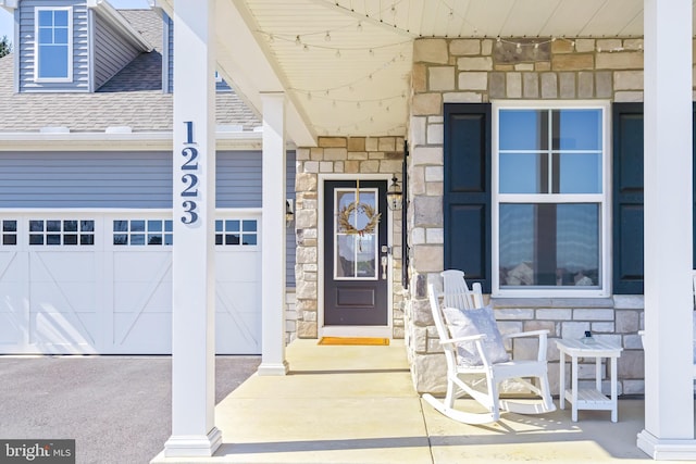 property entrance with stone siding, driveway, and roof with shingles