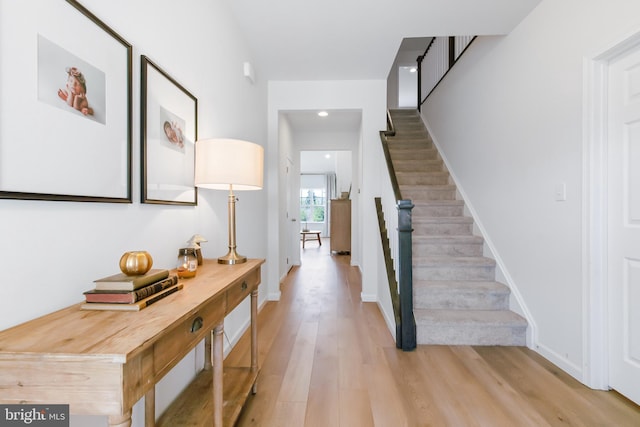 entrance foyer with stairway, baseboards, and light wood finished floors