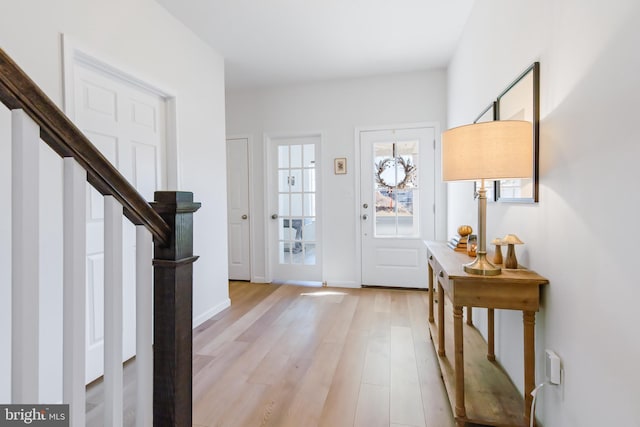 foyer entrance featuring baseboards, light wood-style flooring, and stairs