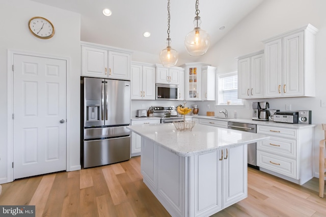 kitchen with a center island, white cabinetry, stainless steel appliances, and lofted ceiling