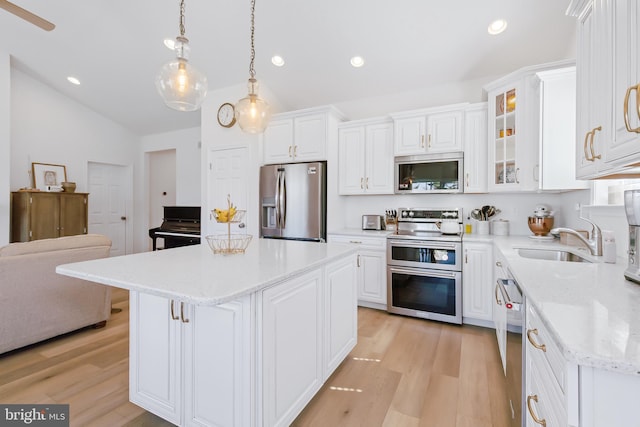 kitchen with a sink, stainless steel appliances, light wood-style floors, and white cabinetry