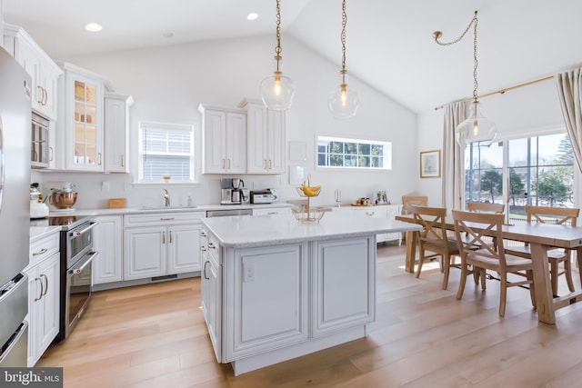 kitchen with a center island, range with two ovens, plenty of natural light, and a sink