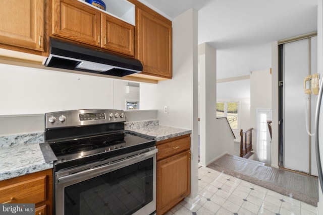 kitchen featuring electric range, light stone countertops, brown cabinetry, and under cabinet range hood