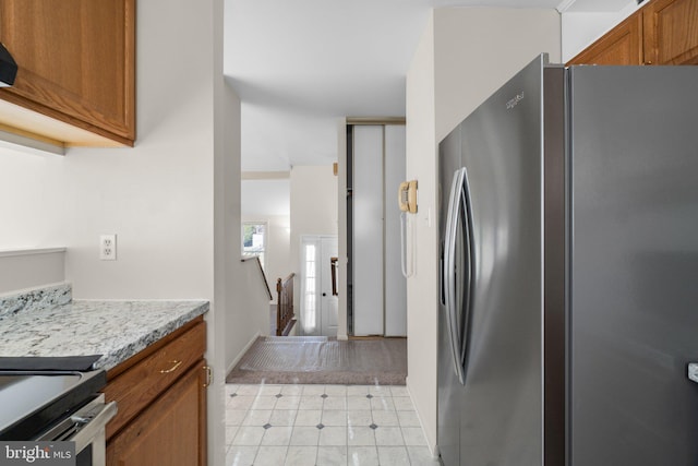 kitchen with light countertops, brown cabinetry, and freestanding refrigerator