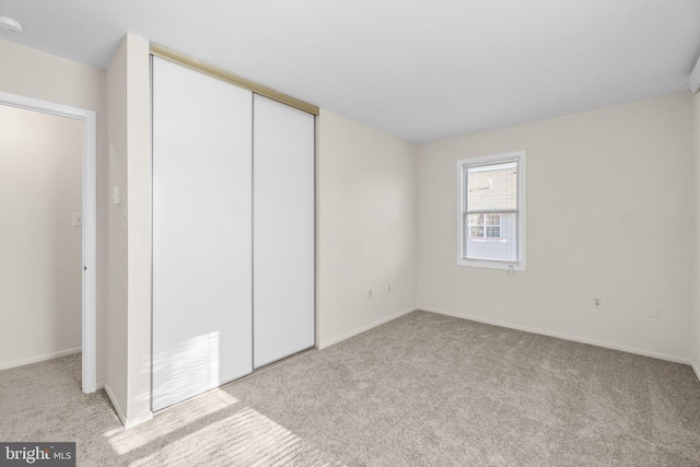 unfurnished bedroom featuring a closet, carpet floors, and baseboards