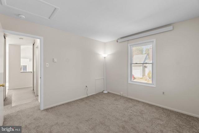 spare room featuring attic access, carpet, and baseboards