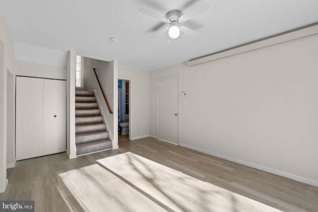 basement with a ceiling fan, stairway, wood finished floors, and baseboards