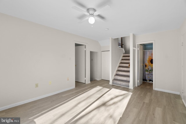 unfurnished living room with baseboards, ceiling fan, stairs, and light wood finished floors