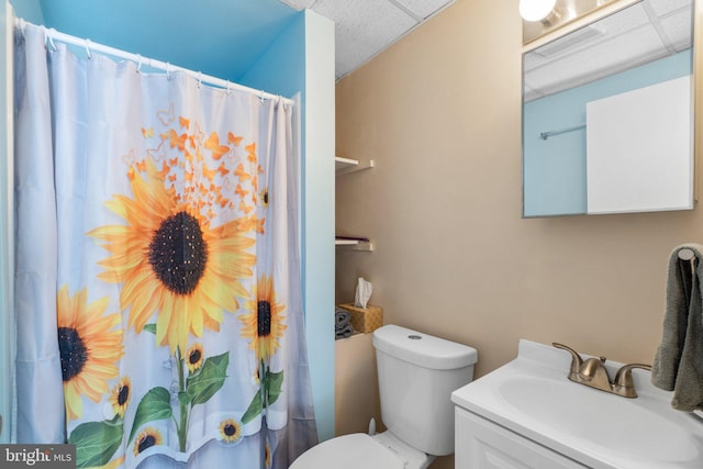 bathroom featuring a shower with curtain, toilet, vanity, and a drop ceiling