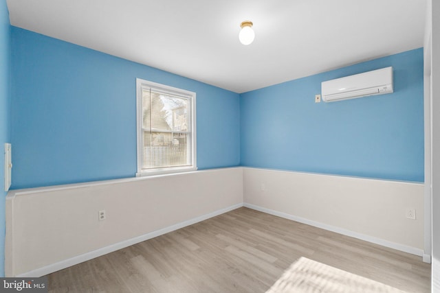 unfurnished room featuring baseboards, wood finished floors, and a wall mounted AC