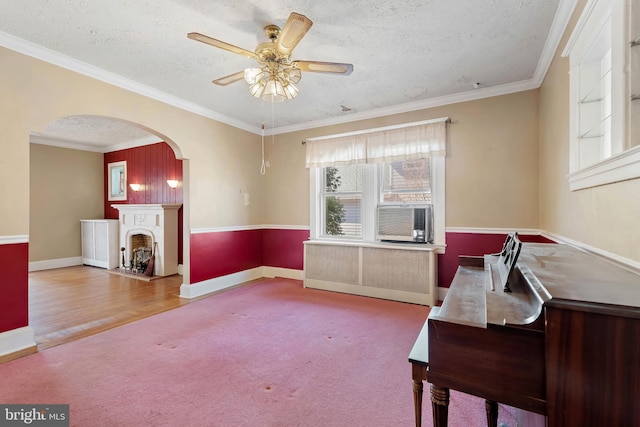 interior space featuring ceiling fan, carpet floors, a fireplace, arched walkways, and a textured ceiling