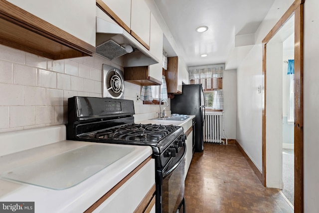 kitchen with backsplash, radiator, black gas range, light countertops, and a sink