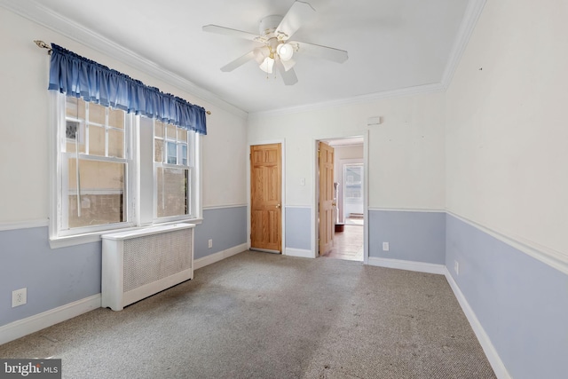 carpeted spare room featuring ceiling fan, radiator, baseboards, and ornamental molding