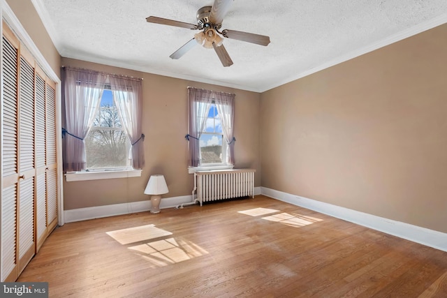 unfurnished bedroom with a closet, a textured ceiling, wood finished floors, and radiator heating unit