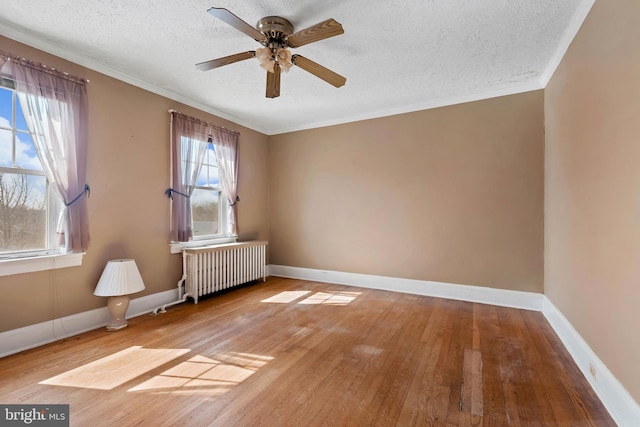 spare room with baseboards, radiator heating unit, ornamental molding, wood-type flooring, and a textured ceiling