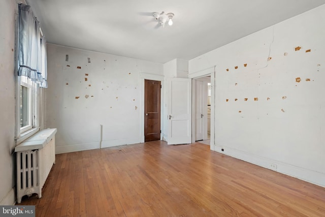 empty room featuring radiator heating unit and light wood finished floors