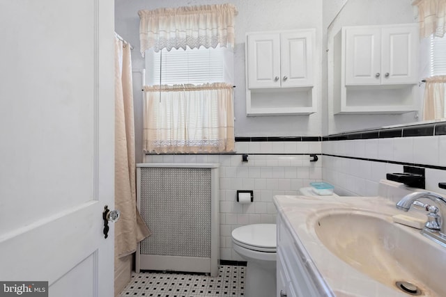 bathroom featuring vanity, tile walls, toilet, and a wainscoted wall