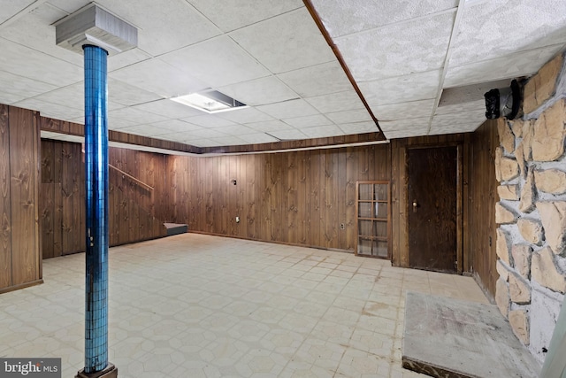 finished below grade area featuring tile patterned floors and wood walls