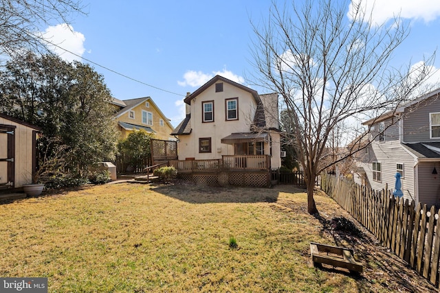 back of property with a wooden deck, stucco siding, a lawn, a storage shed, and an outbuilding