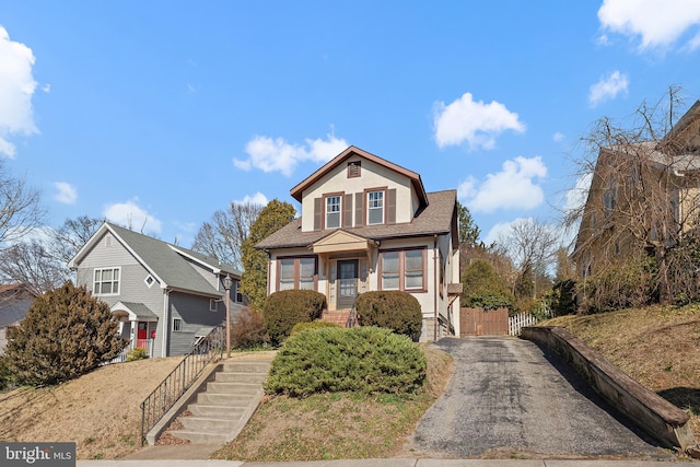 view of front of house featuring a shingled roof, fence, stucco siding, driveway, and a gate