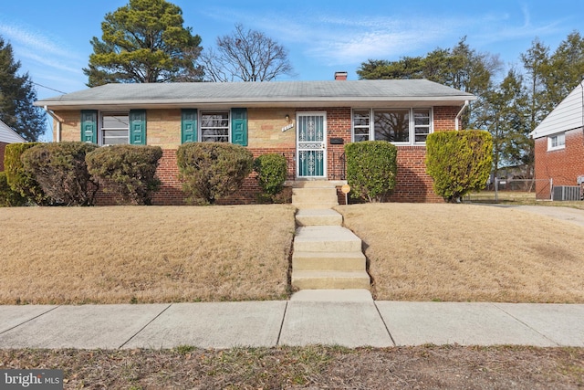 ranch-style home with brick siding, fence, central AC, a front yard, and a chimney