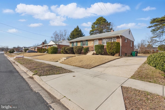 single story home with brick siding, concrete driveway, and a chimney