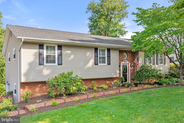 split foyer home with brick siding, a front lawn, and a shingled roof