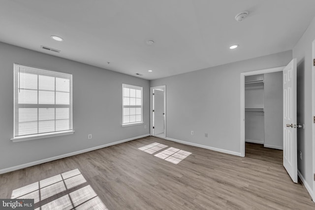 unfurnished bedroom with recessed lighting, visible vents, baseboards, light wood-style floors, and a walk in closet