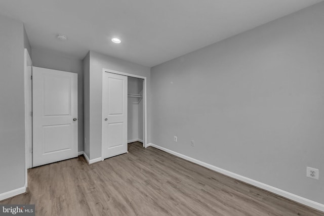 unfurnished bedroom with recessed lighting, a closet, baseboards, and wood finished floors