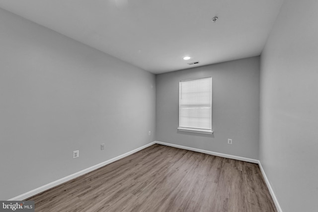 empty room featuring baseboards, visible vents, and wood finished floors