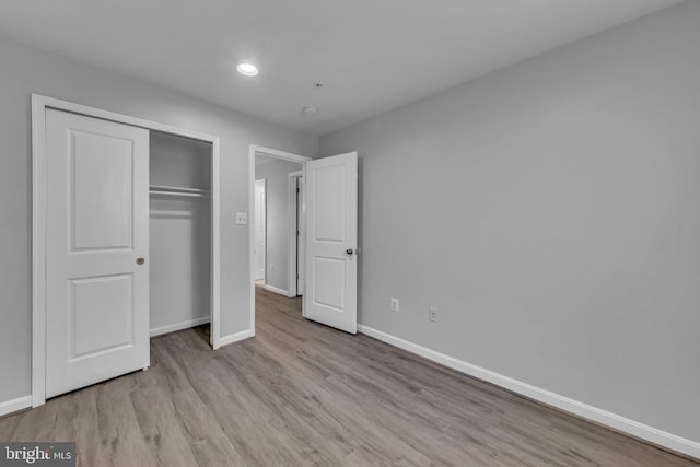 unfurnished bedroom with a closet, baseboards, wood finished floors, and recessed lighting