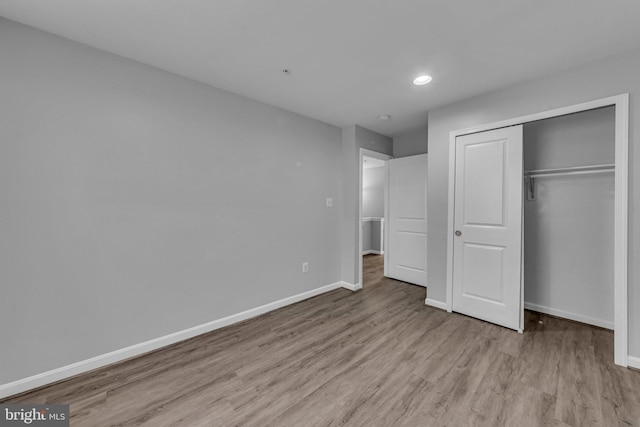 unfurnished bedroom featuring recessed lighting, a closet, baseboards, and wood finished floors