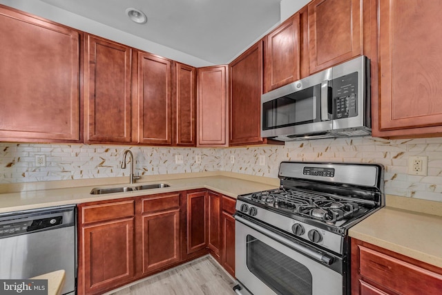 kitchen featuring light countertops, backsplash, appliances with stainless steel finishes, light wood-style floors, and a sink