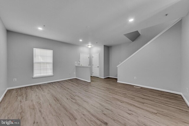 unfurnished living room with recessed lighting, baseboards, and wood finished floors