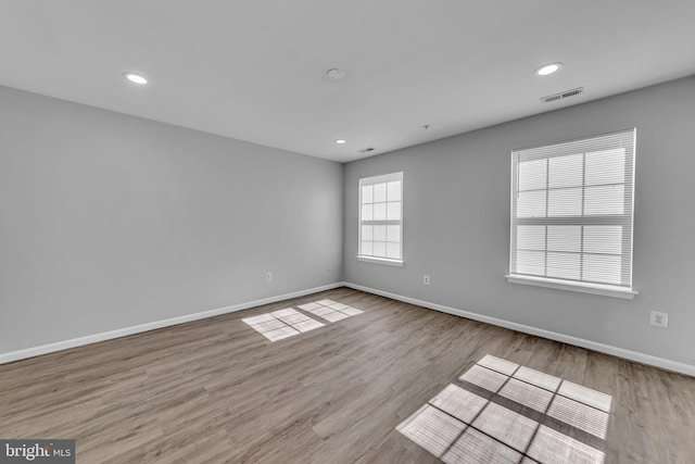 spare room with baseboards, visible vents, wood finished floors, and recessed lighting