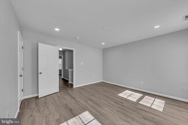 spare room with recessed lighting, visible vents, baseboards, and wood finished floors