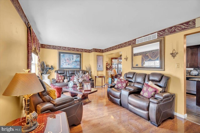 living room featuring wood finished floors, visible vents, and baseboards