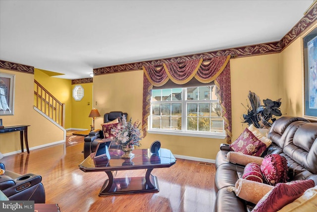 living room featuring stairway, wood finished floors, visible vents, and baseboards