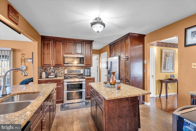 kitchen featuring dark wood-style floors, appliances with stainless steel finishes, a sink, and decorative backsplash